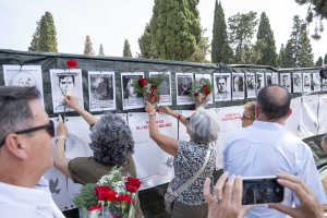 Dos mujeres realizan una ofrenda floral en recuerdo de las víctimas.